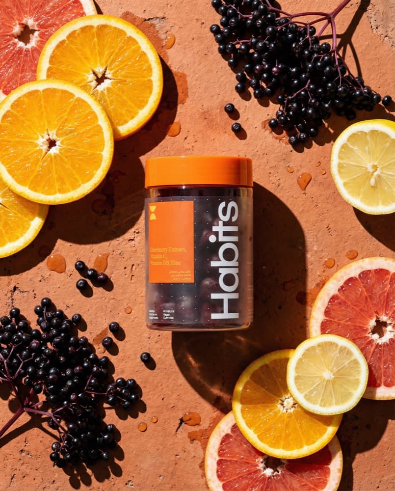 Supplement jar on terracotta with cut citrus and elderberry